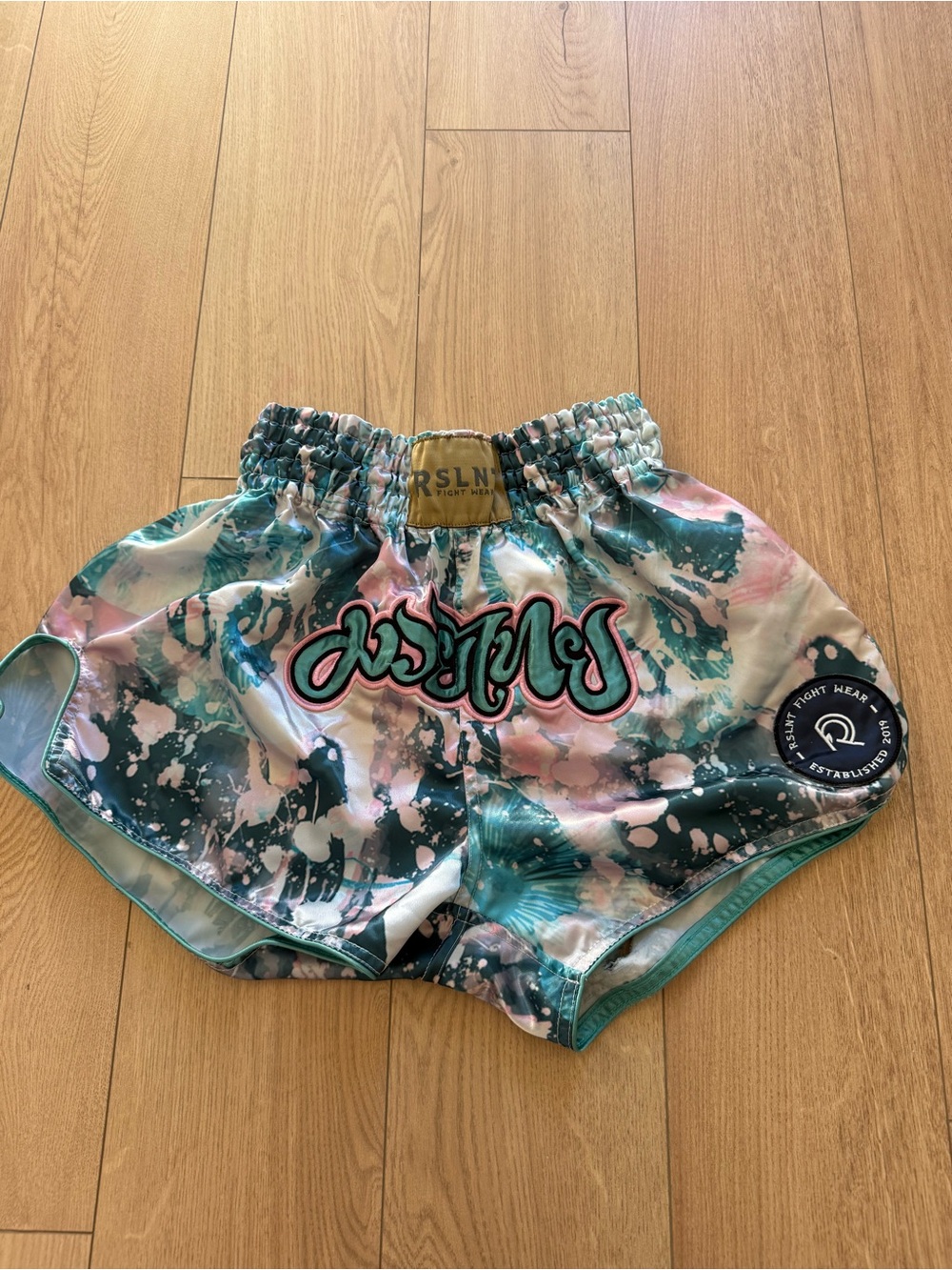 RSLNT Fight Wear Muay Thai shorts in a teal and pink paint-splatter